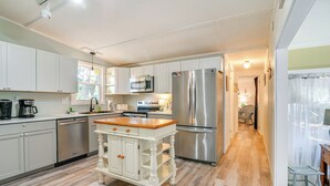 A modern kitchen with white cabinetry, stainless steel appliances, and a wooden island.