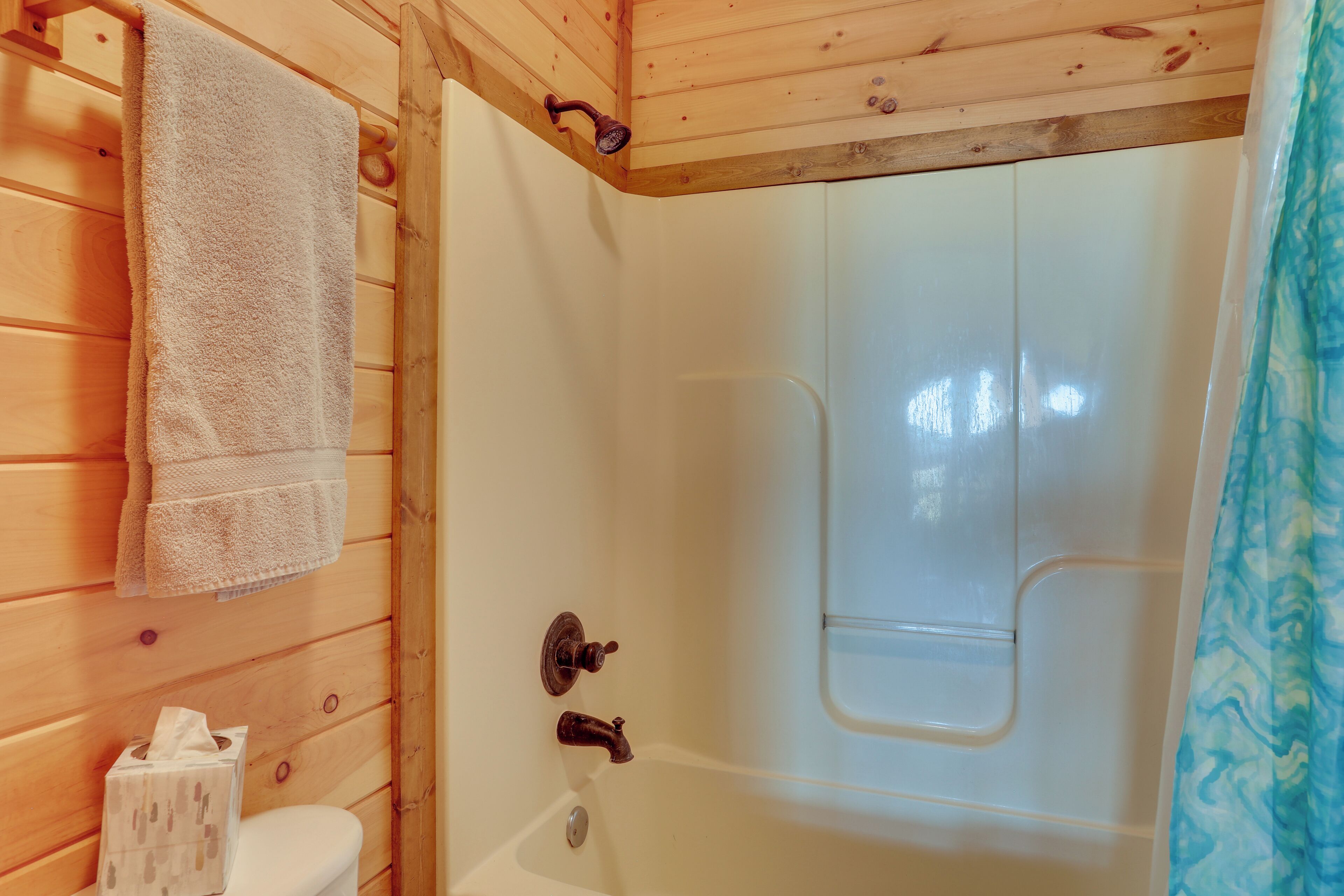Une salle de bain en bois avec une baignoire, des toilettes et une serviette accrochée au mur.