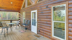 A log cabin with a deck, outdoor seating, and large windows.