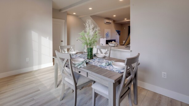 A dining area with a wooden table set for four, surrounded by chairs. - Balconies w/ Scenic River Views: Hammond Townhome! (Hammond)
