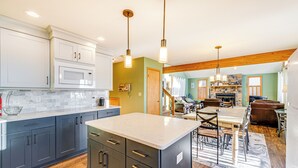 A modern kitchen with dark cabinets, a large island, and pendant lighting. - Beach Access, Private Dock: Arrowhead Lake Cabin (Pocono Lake)