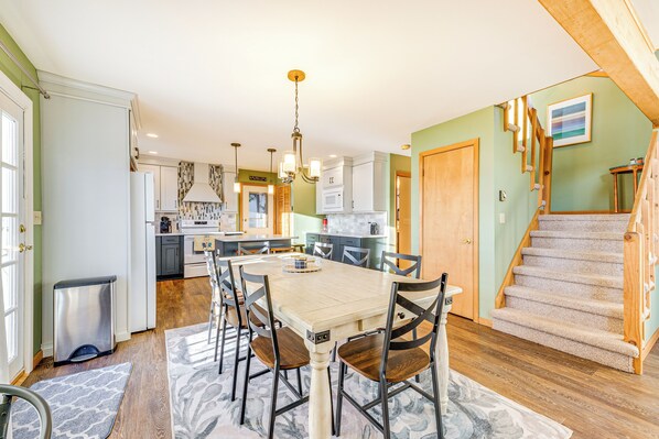 A spacious kitchen with a dining area, wooden staircase, and a view of the living room. - Beach Access, Private Dock: Arrowhead Lake Cabin (Pocono Lake)