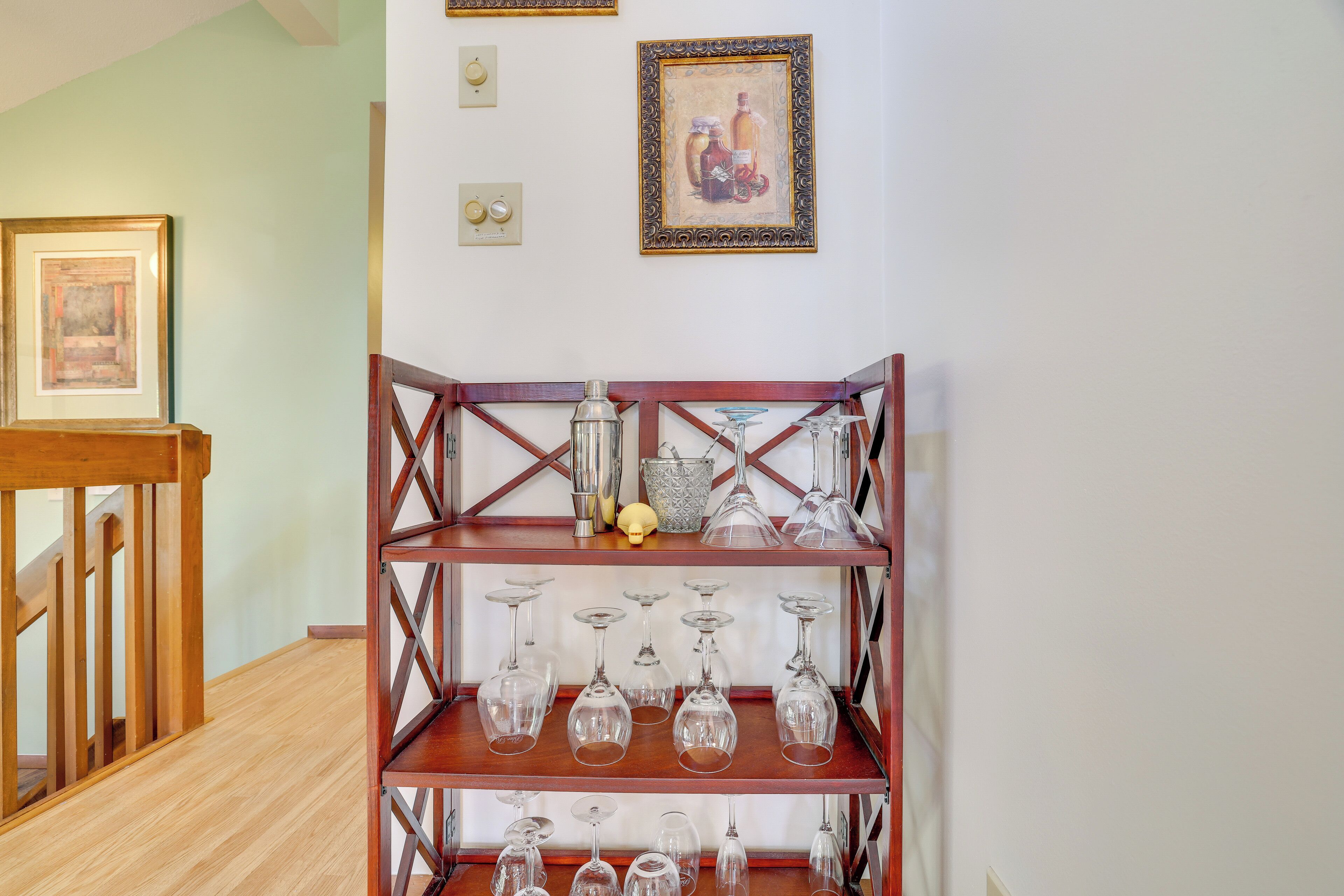 Un escalier en bois avec une étagère en verre où sont posés des verres à vin et des bouteilles.