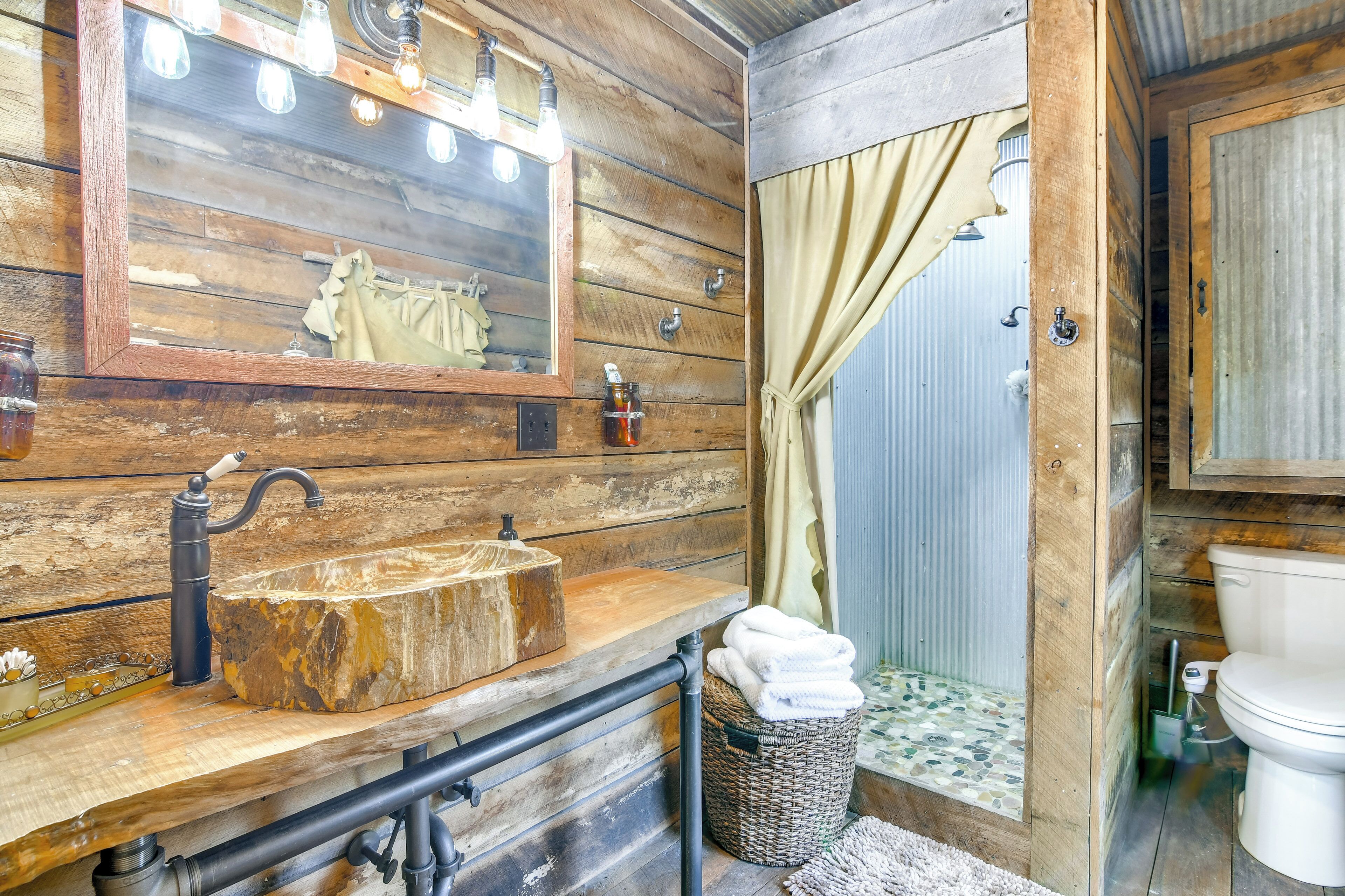 A rustic bathroom with a wooden vanity, a large mirror, and a sink.