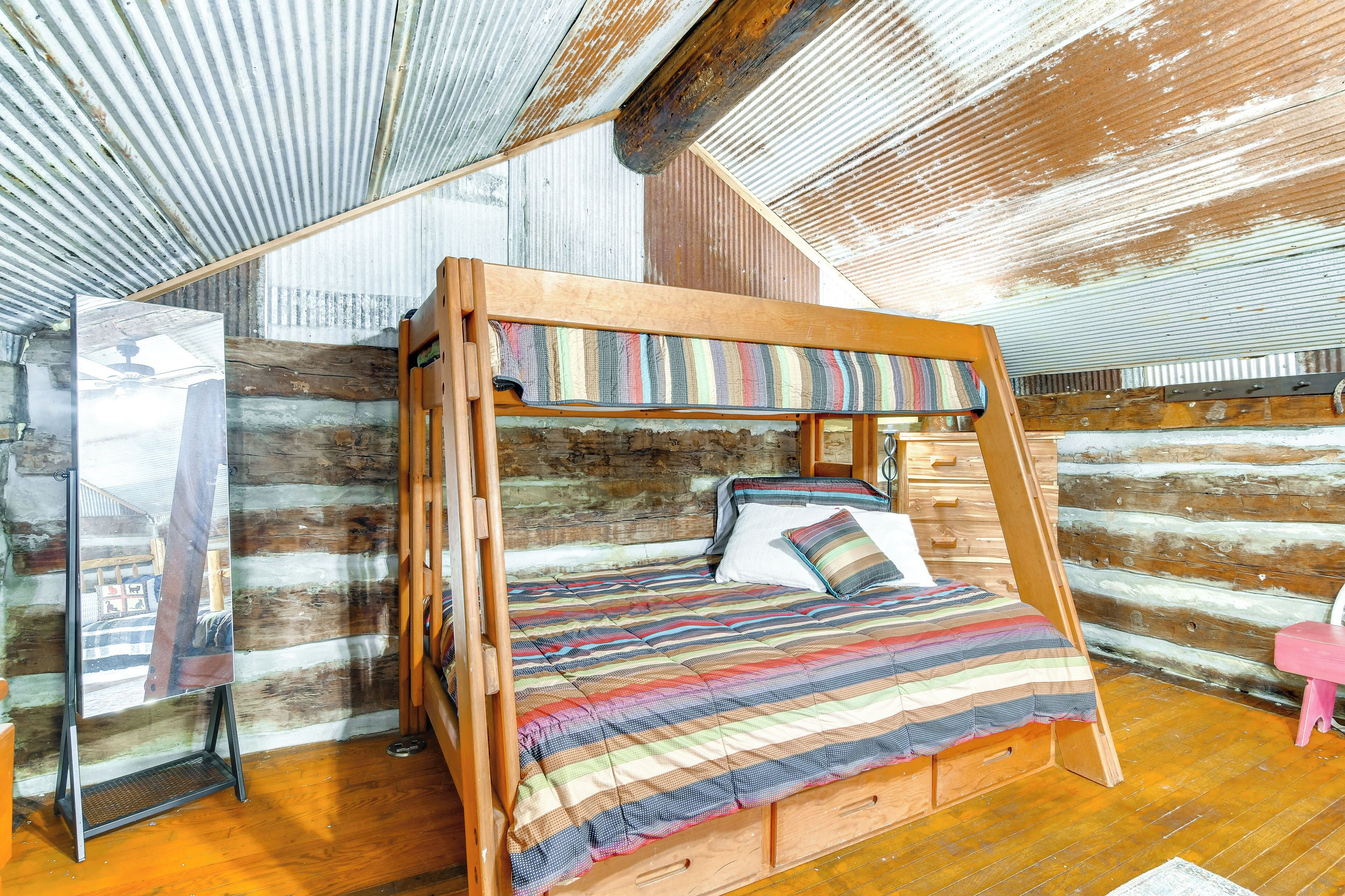 A bunk bed with a striped blanket, wooden headboard, and a small wooden dresser.