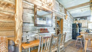 L  ’intérieur d’un chalet rustique, avec une table à manger en bois, des chaises et un coin cuisine.