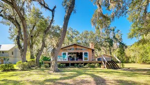 A modern house with a large deck, surrounded by trees and a well-maintained lawn. - Waterfront Home w/ Boat Dock & Slip in Old Town! (Old Town)