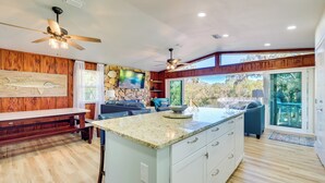 A spacious kitchen with a large island, wooden accents, and a stone accent wall. - Waterfront Home w/ Boat Dock & Slip in Old Town! (Old Town)