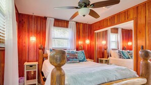 A wooden-paneled bedroom with a bed, bedside tables, a ceiling fan, and a large mirror. - Waterfront Home w/ Boat Dock & Slip in Old Town! (Old Town)