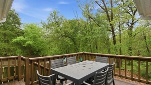 Eine Holzterrasse mit Tisch und Stühlen, umgeben von Bäumen.
