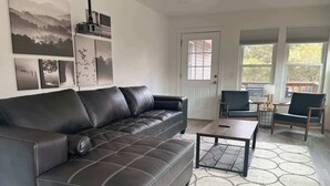 Ein Wohnzimmer mit einer schwarzen Ledersofa, einem Couchtisch und einem gemusterten Teppich.