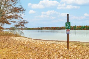 A lakeside scene with a sign indicating swimming is at your own risk. - Steps to Long Lake: Cabin w/ Patio in Harrison! (Harrison)
