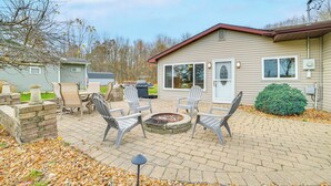 A patio with outdoor seating, a fire pit, and a house in the background. - Steps to Long Lake: Cabin w/ Patio in Harrison! (Harrison)