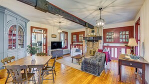 A spacious living room with a wooden dining table, comfortable seating, a fireplace, and a television. - Walk to Creek: Mount Joy Home Near Nook Sports (Mount Joy)