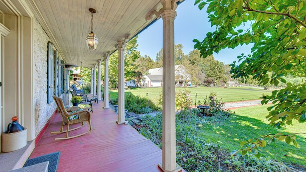 A covered porch with red flooring, white columns, and a rocking chair. - Walk to Creek: Mount Joy Home Near Nook Sports (Mount Joy)