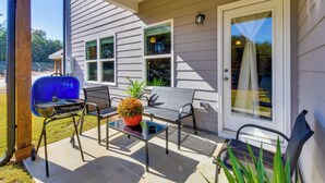 Une terrasse avec un barbecue, des chaises et une table.