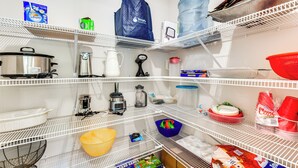 Uma despensa bem organizada, com diversos alimentos, eletrodomésticos e recipientes de armazenamento.