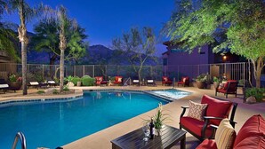 A poolside area with a pool, lounge chairs, and a seating area with red sofas and a table. - Fully Appointed Upper Floor Condo with Mountain-Canyon-Pool-Golf Course Views (Tucson)