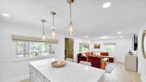 A spacious kitchen with white cabinetry, a marble island, and pendant lighting. - Updated 4th row beach home, private pool, fenced in yard, and putting green! (Hilton Head)