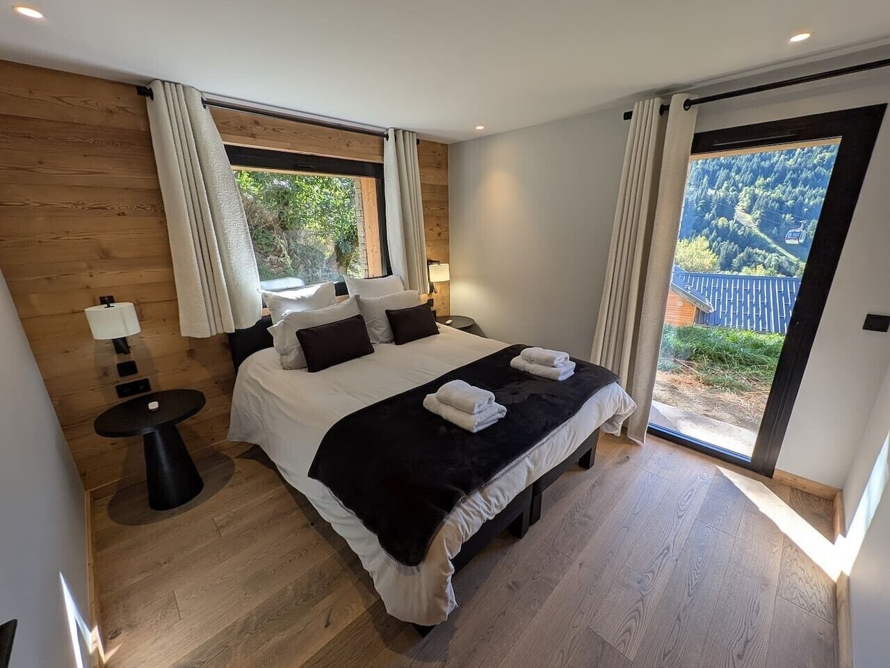 Une chambre à coucher avec un grand lit, une petite table et une vue sur un paysage montagneux.