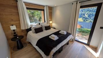 Une chambre à coucher avec un grand lit, une petite table et une vue sur un paysage montagneux.