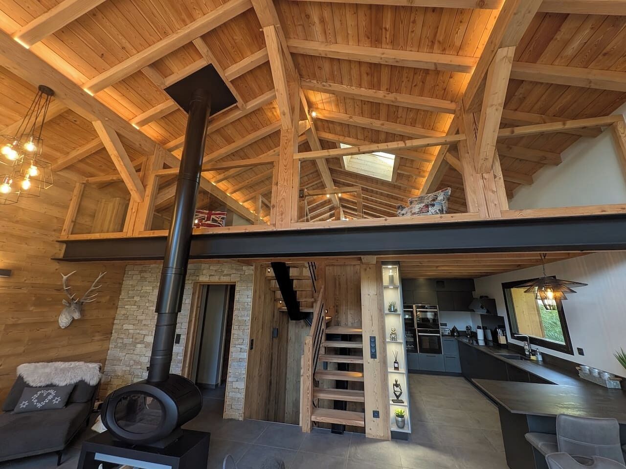 Un intérieur spacieux avec un plafond haut, une cheminée, un escalier et un coin cuisine.