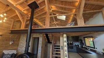 Un intérieur spacieux avec un plafond haut, une cheminée, un escalier et un coin cuisine.
