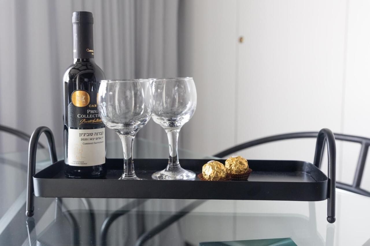 A bottle of wine and two glasses on a tray with chocolates.