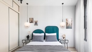 Camera da letto moderna con un letto grande, due comodini, una scrivania e una finestra con tende.