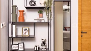 Un soggiorno moderno con un'unità scaffale in metallo nero, uno specchio e una porta in legno.