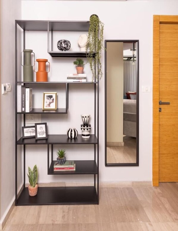 A modern living room with a black metal shelving unit, a mirror, and a wooden door. - JLM Rooftop luxury apartment (Jerusalem)