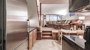 A compact living space with a kitchenette, a sofa, a coffee table, and a TV mounted on the wall. - One bedroom Cascades C-7, sleeping 6, fireplace! (Newry)