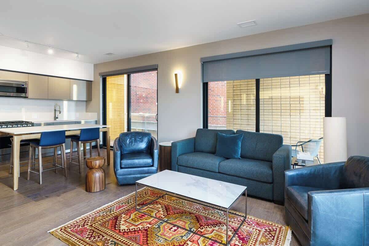 A modern living room with a sofa, chairs, a coffee table, and a patterned rug.