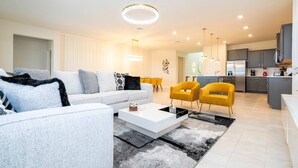 Un salon moderne avec un canapé blanc, une table basse et un fauteuil jaune.