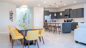 Une cuisine moderne avec des meubles gris, un réfrigérateur en acier inoxydable et un îlot central doté de tabourets de bar.