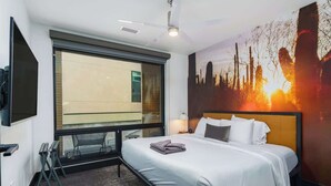 Et hotelværelse med en stor seng, et bybillede-motiv, et vindue og et fladskærms-tv.