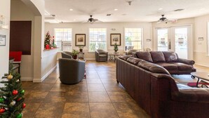 A spacious lobby with a brown leather sofa, a gray armchair, and a small table with a potted plant.