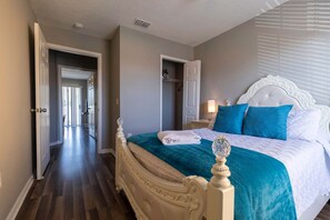 A bedroom with a large bed, a walk-in closet, and a hallway leading to another room. - 3BR Townhome Steps From Theme Parks Sleeps 6 (Kissimmee)