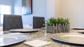 A dining table set with plates and a centerpiece of a wooden block with the word "HOME".