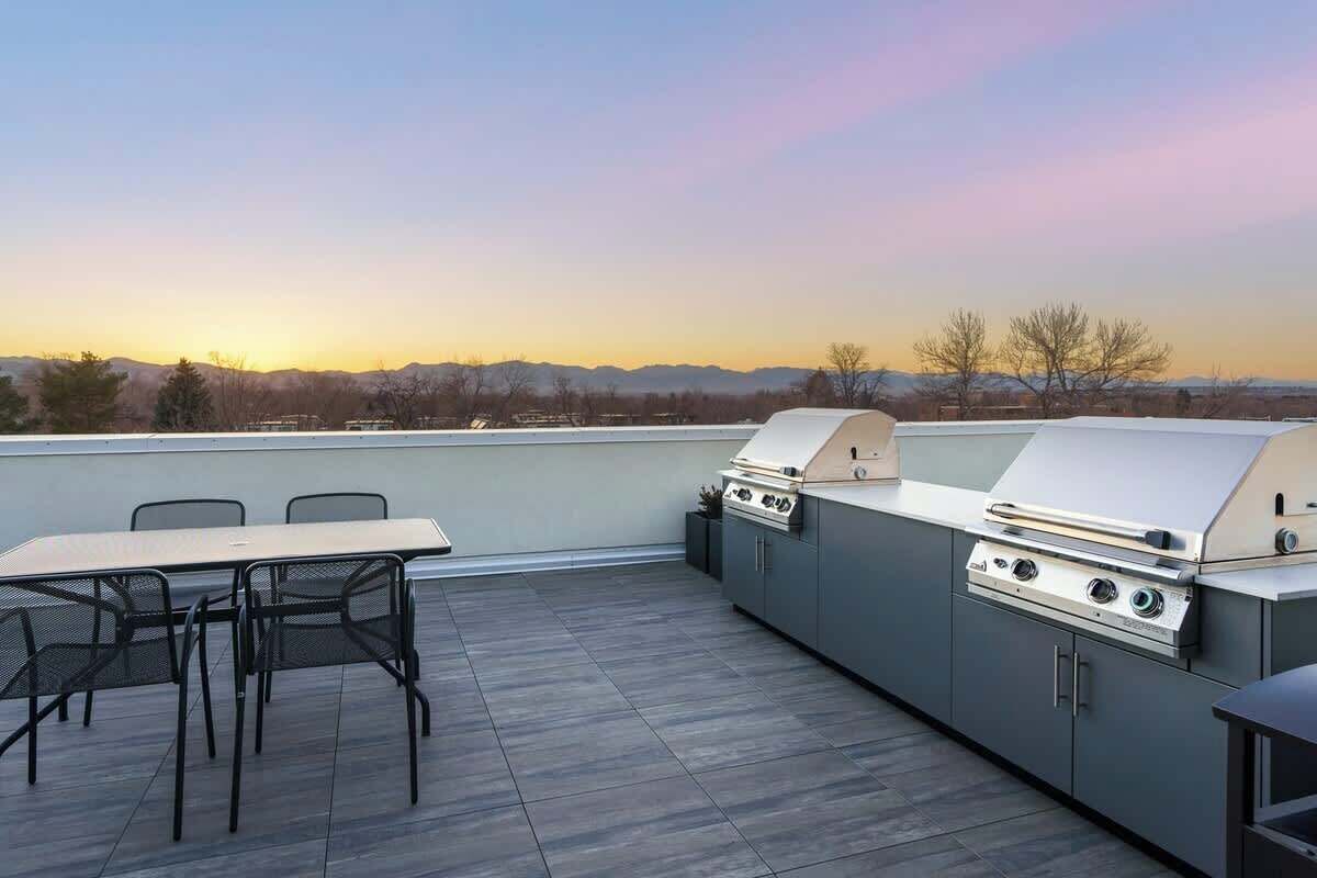 Une terrasse extérieure avec un barbecue, une table et des chaises.