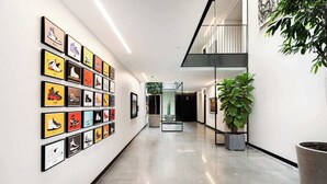 A hallway with framed artwork on the walls, a potted plant, and a staircase. - Designer Studio w/ Balcony & Rooftop Patio on Tennyson Street (Denver)