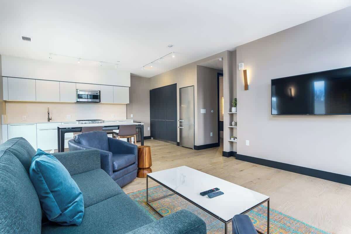 Een moderne woonkamer met een bank, een salontafel en een flatscreen televisie die aan de muur is bevestigd.
