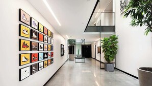 A hallway with framed shoe designs on the wall, a potted plant, and a staircase. - Sleek Tennyson St Flat w/ Balcony & Views (Denver)