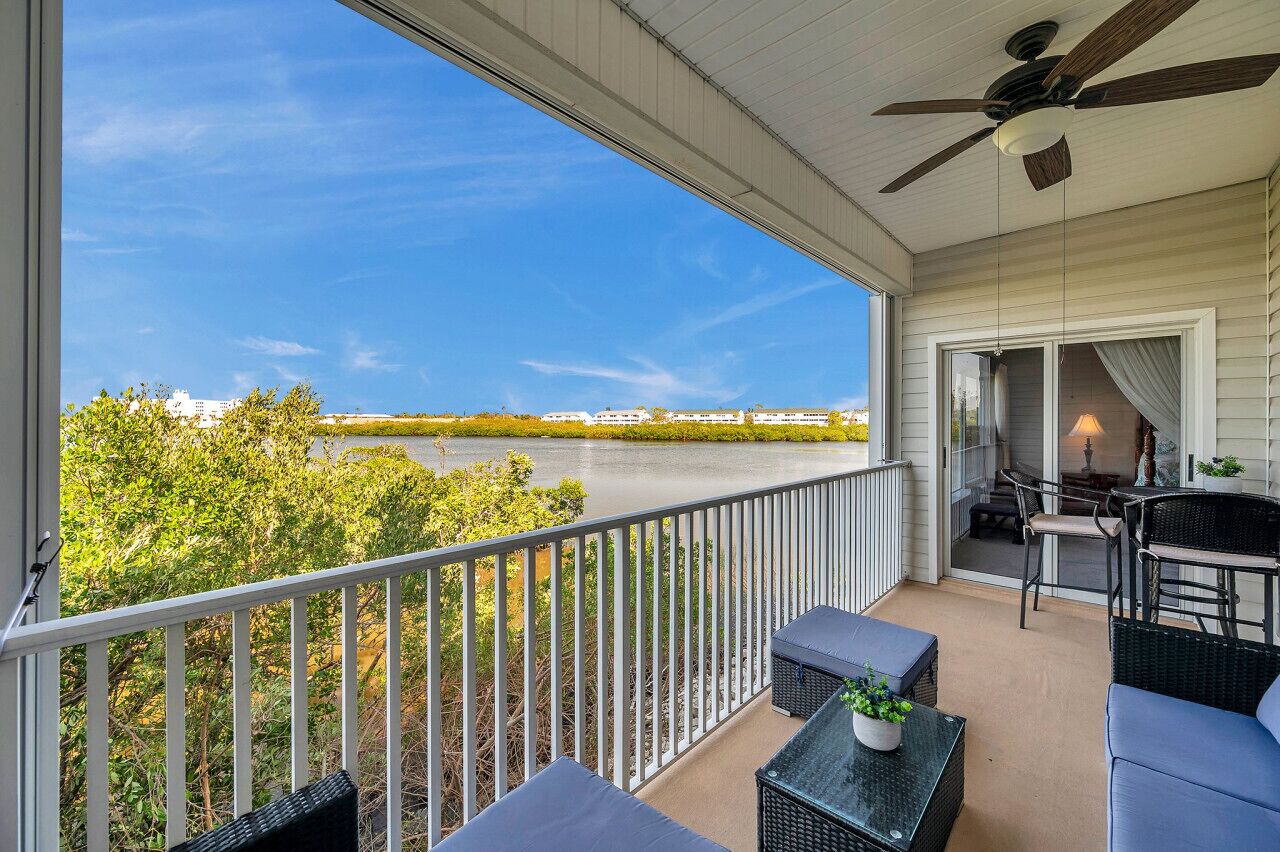 Un balcon avec vue sur une rivière, des meubles d’extérieur et un ventilateur de plafond.