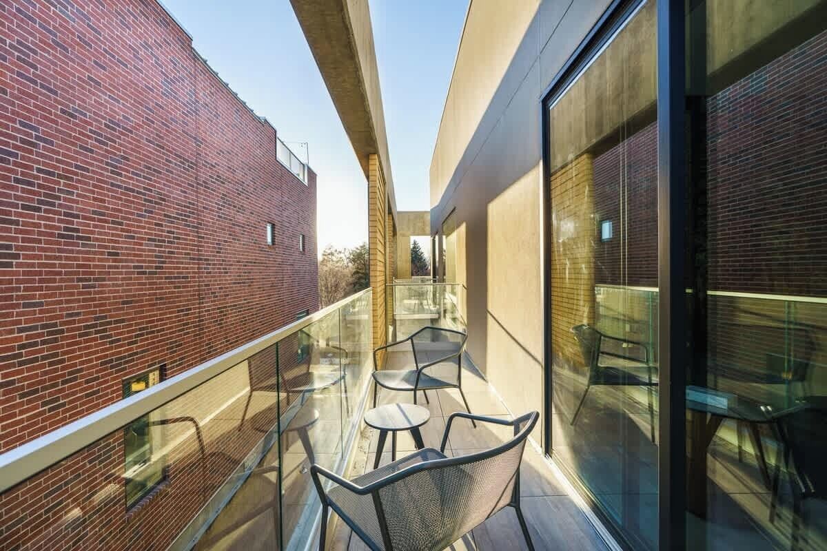 A balcony with glass railings, a brick wall, and a modern building facade.