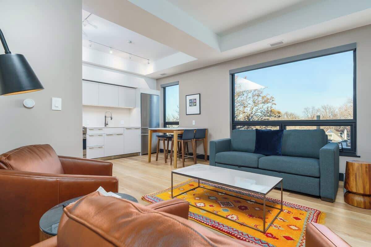 Un salon moderne avec un canapé, une table basse et une grande fenêtre donnant sur l’extérieur.
