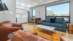 Un salon moderne avec un canapé, une table basse et une grande fenêtre donnant sur l’extérieur.