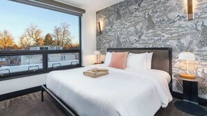 Habitació d'hotel moderna amb un llit gran, vista a la ciutat i un mur amb dibuixos.