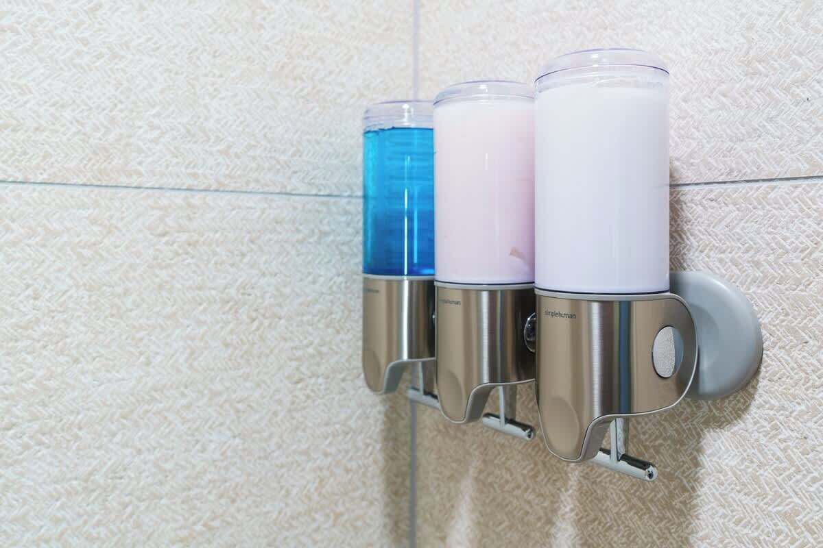 Een zeepdispenser bevestigd aan de muur, met drie verschillende gekleurde zeepjes.
