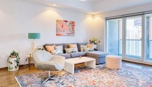 A modern living room with a sofa, coffee table, and a large window. - Lux CanalView Apt in Iconic Churchill Tower (Dubai)